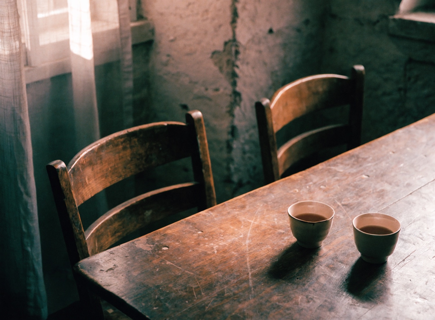 Two cups of tea on a kitchen table by a window, a conversation just paused